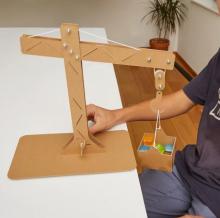 cardboard constructed crane on a table, holding basket of colourful cubes 