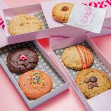 Pink table and boxes/trays with 6 different flavoured cookies in them